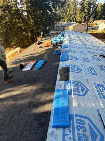 Bundles of shingles staged on new underlayment